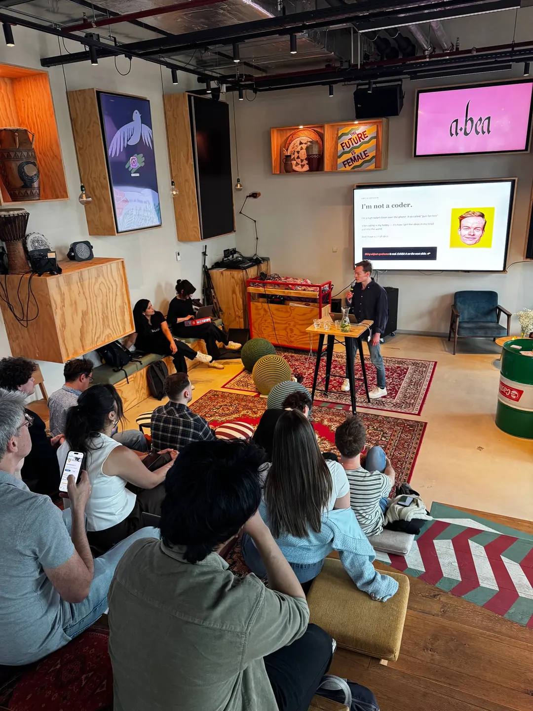 A community builder presenting a project to the audience at the Vibe Coding Open Mic in Amsterdam.