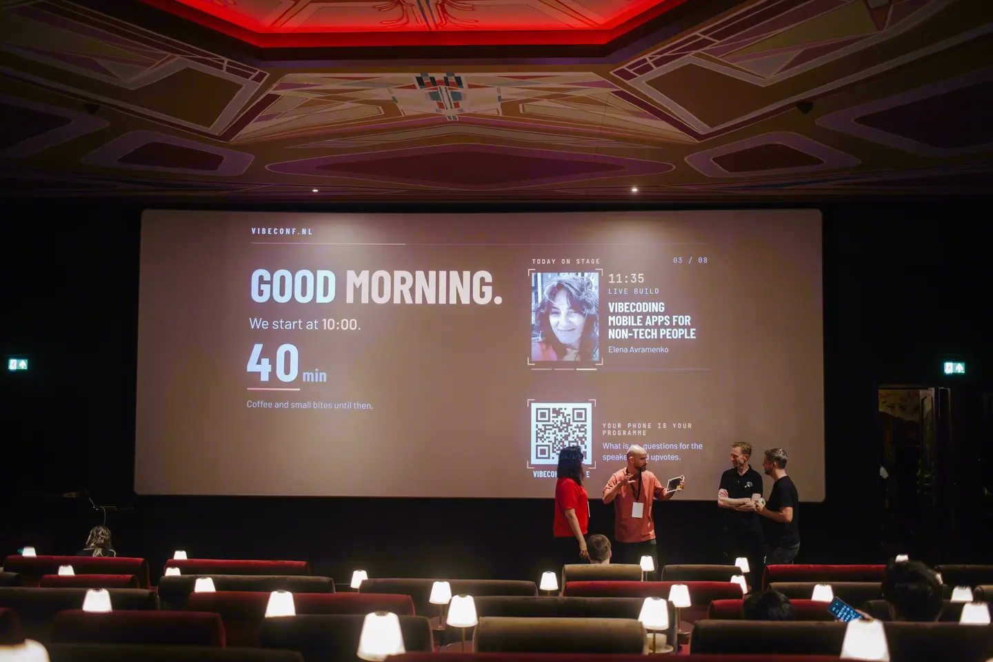 The stage before the opening, the big screen greeting the room with Good morning.